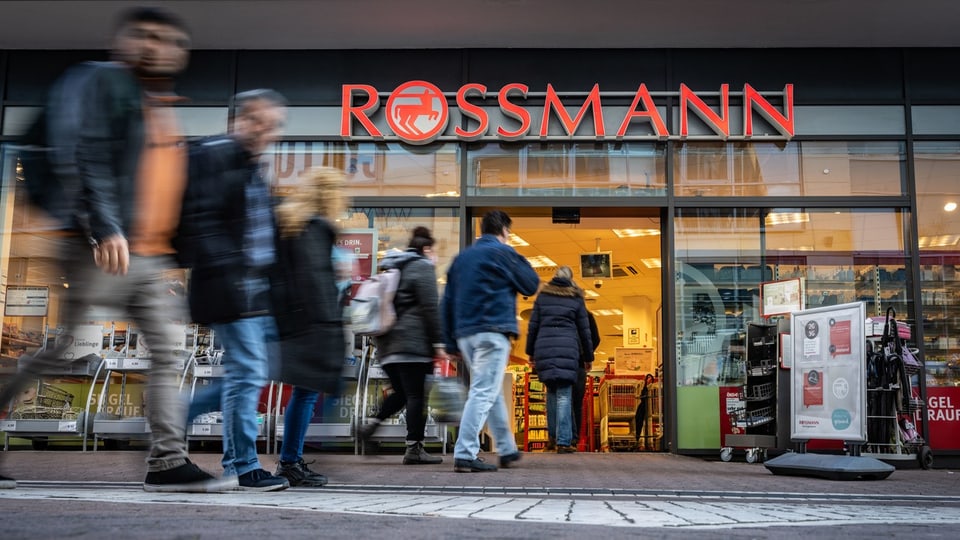 Menschen betreten und verlassen ein Rossmann-Geschäft.