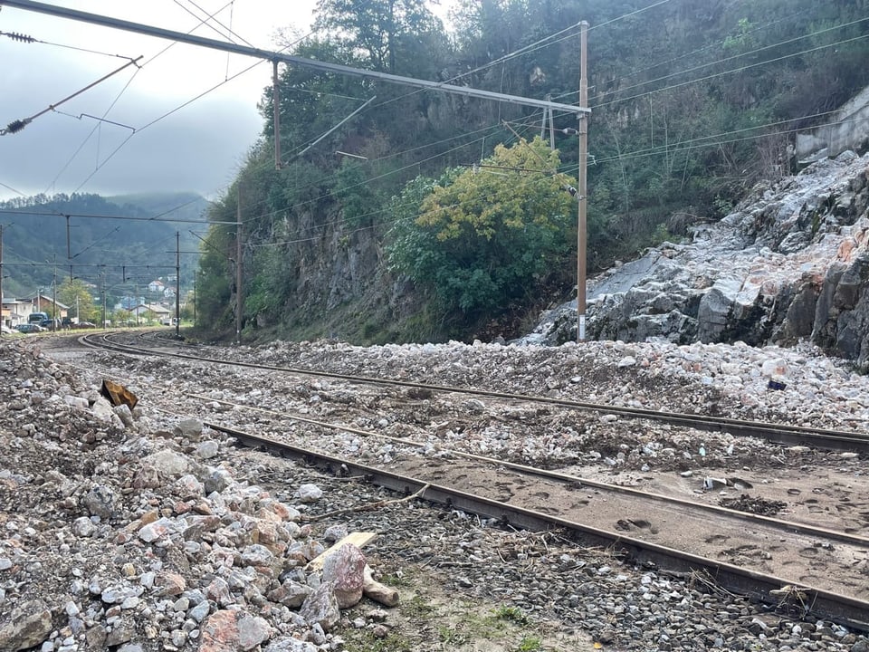 Eisenbahngleise neben Felsrutsch mit Geröll.