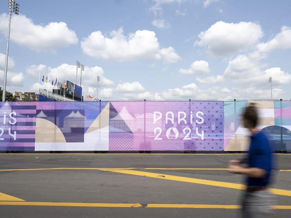 Werbetafel für Paris 2024 mit Passant im Vordergrund.