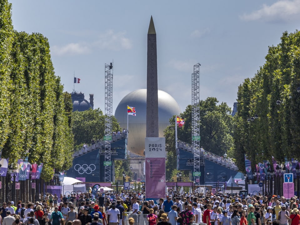 Menschenmenge vor dem Obelisken in Paris mit Paris 2024-Banner.