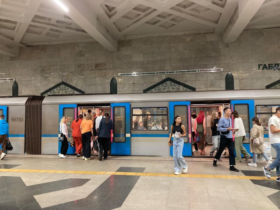 Menschen steigen in der U-Bahn-Station in einen blauen Zug ein.