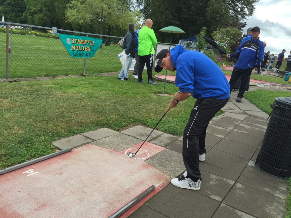 Ein Minigolfer steht hochkonzentriert am Abschlag