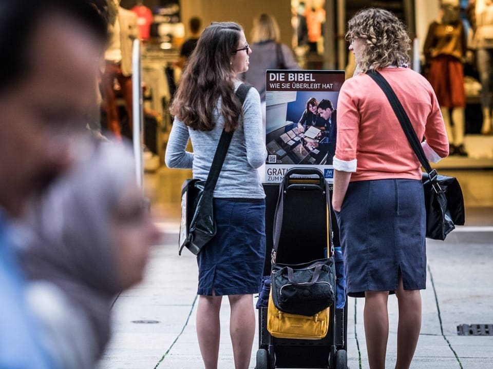 Zwei Frauen stehen neben einem Bücherstand in einer Einkaufspassage.