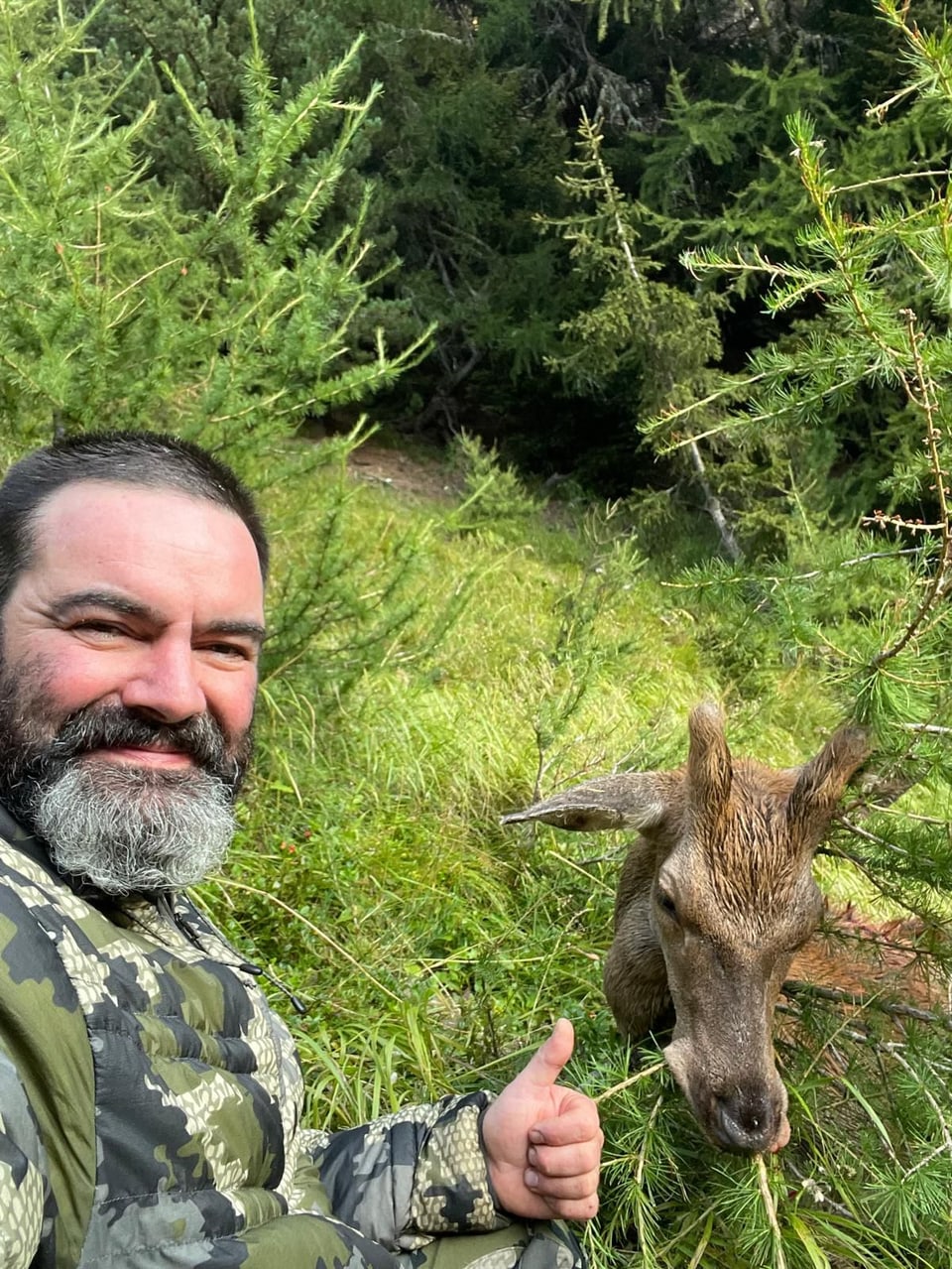 Mann macht Selfie mit Reh im Wald.