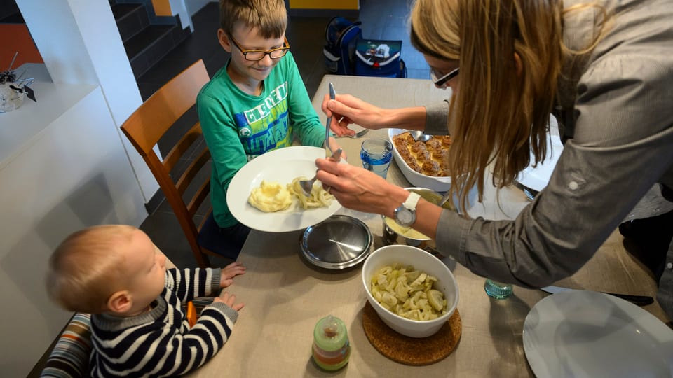 Eine Mutter beim Essen mit ihren beiden Kleinkindern 