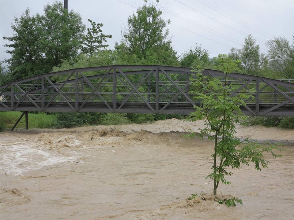 Ein reissender Fluss, darüber steht eine Metallbrücke.