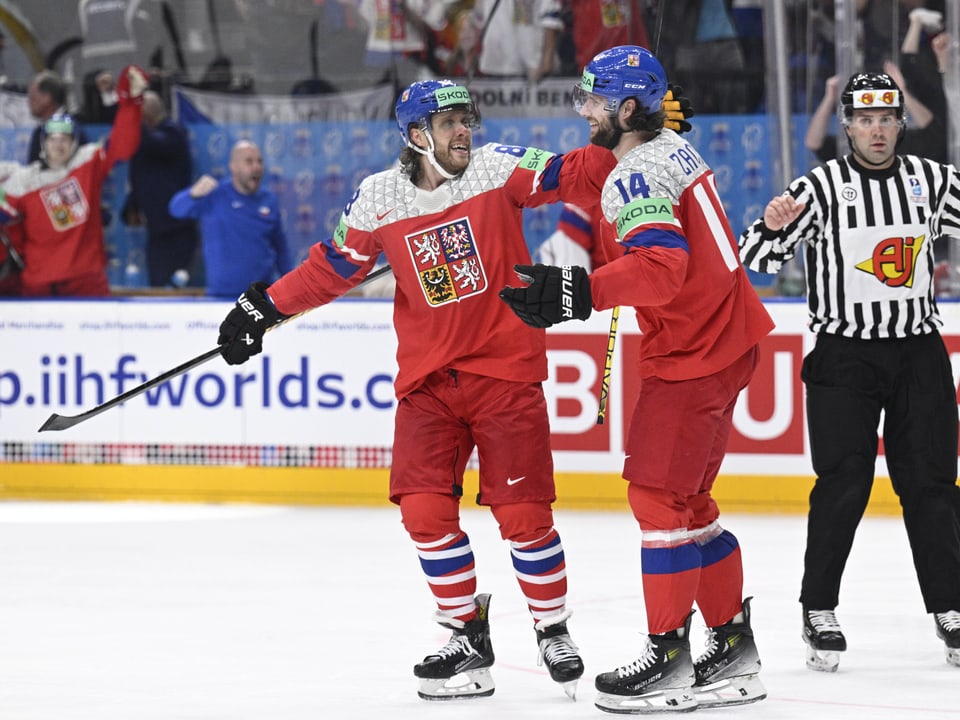 Zwei Eishockeyspieler der tschechischen Nationalmannschaft feiern auf dem Eis, Schiedsrichter im Hintergrund.