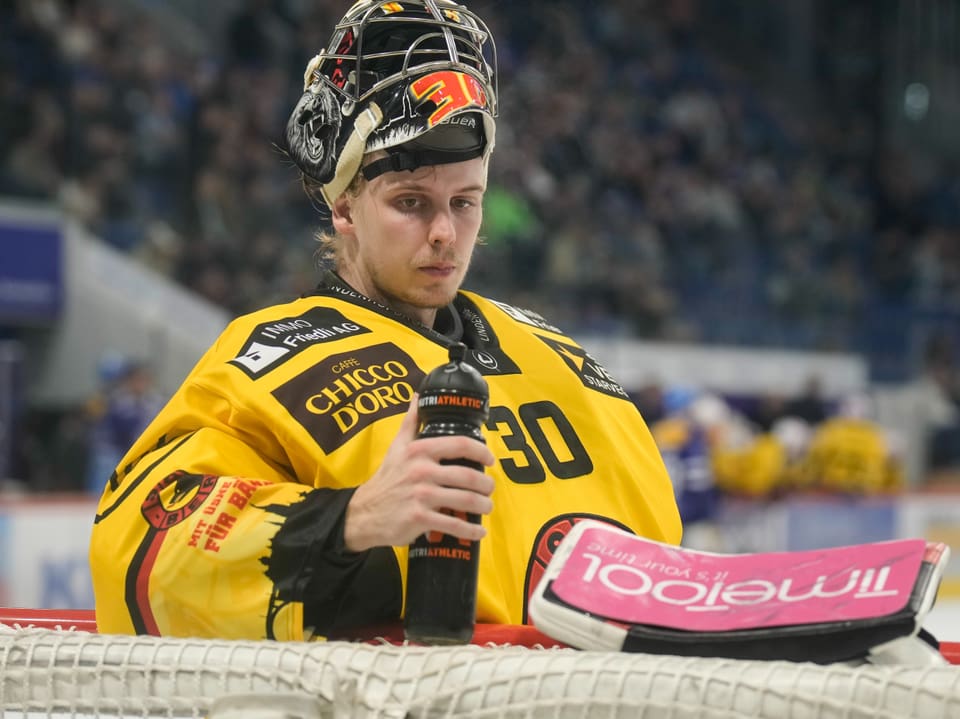 Eishockeytorwart in gelbem Trikot hält Trinkflasche.