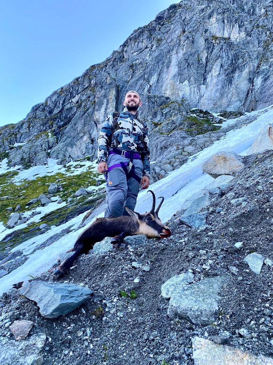 Mann auf einem felsigen Berghang mit einer Bergziege.