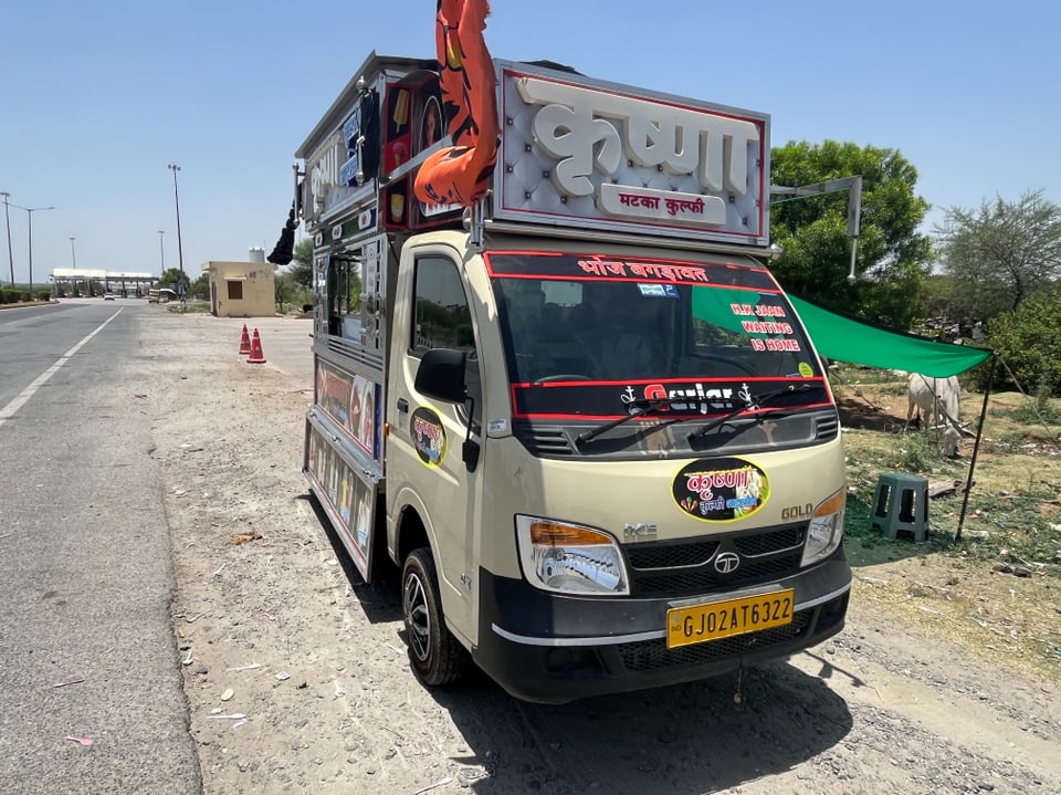 Indischer Lieferwagen auf einer Landstrasse, dekoriert mit bunten Schildern.