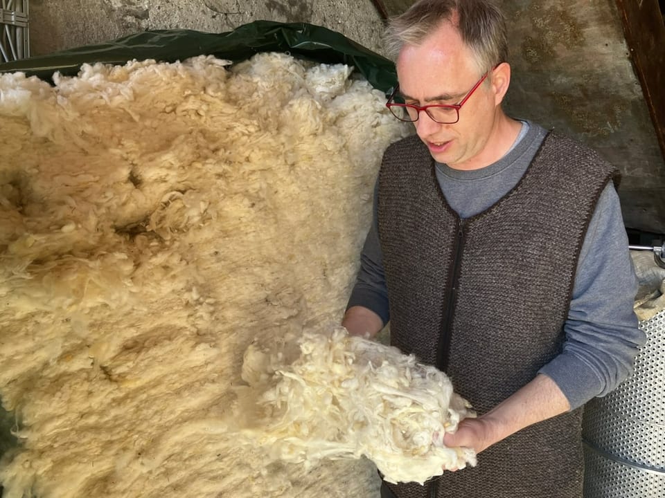 Mann hält Wolle in den Händen.