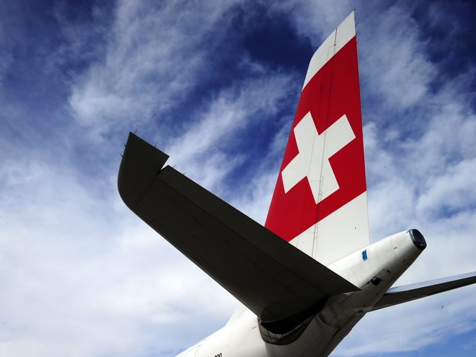 Flugzeugheck mit Schweizer Flagge unter blauem Himmel.