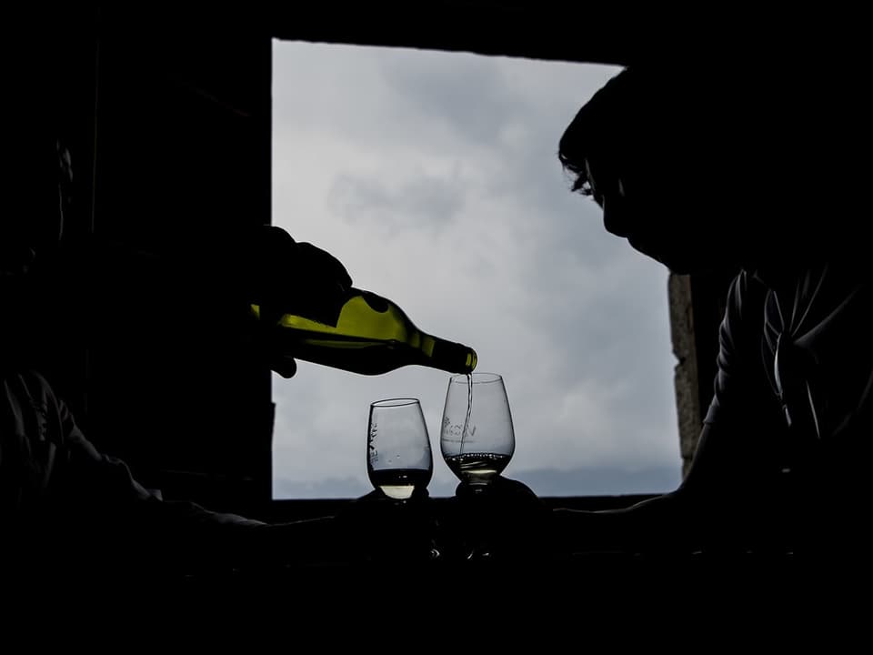 Silhouetten zweier Personen, Wein wird eingeschenkt.