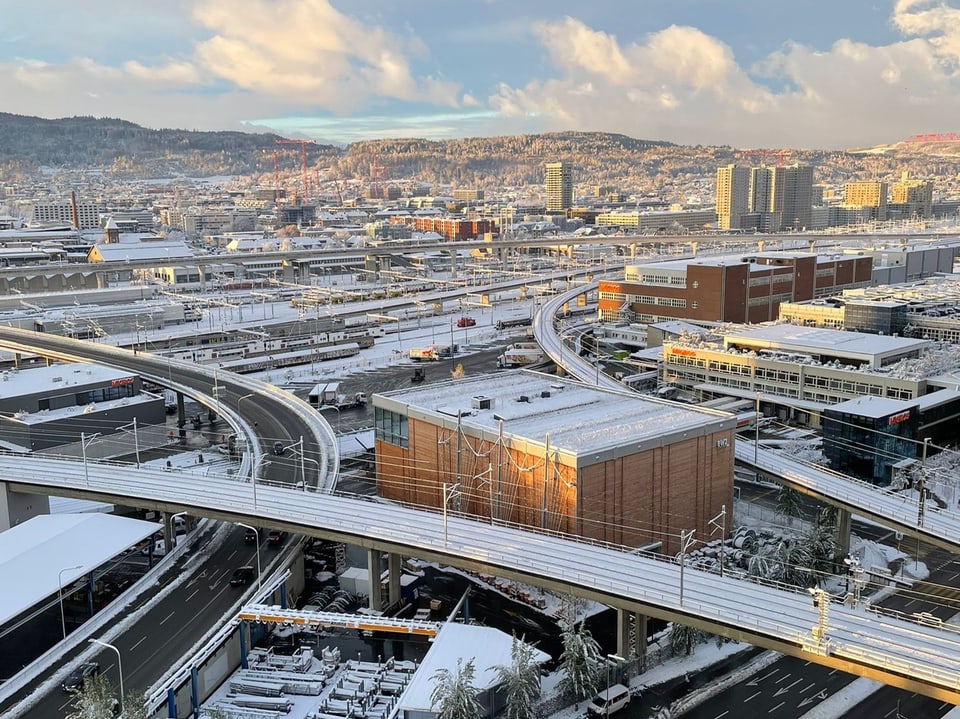 Verschneite Stadtlandschaft mit Autobahn-Überführungen.