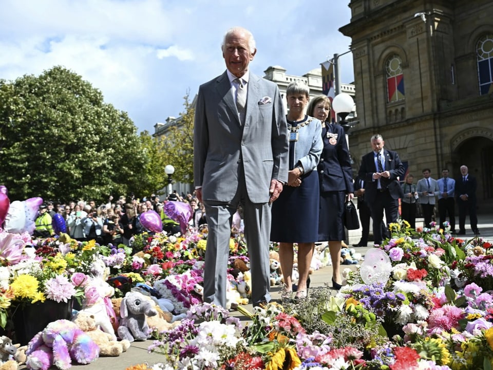 König Charles schreitet durch ein Meer von niedergelegten Blumen und Plüschtieren.