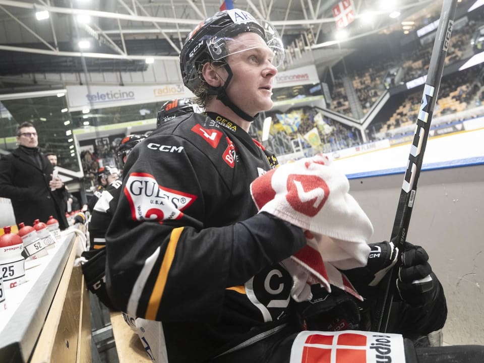 Eishockeyspieler auf der Bank mit Handtuch.