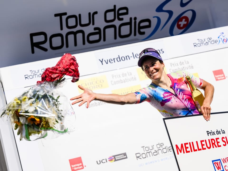 Radfahrerin wirft Blumenstrauss auf einer Siegerehrung der Tour de Romandie.