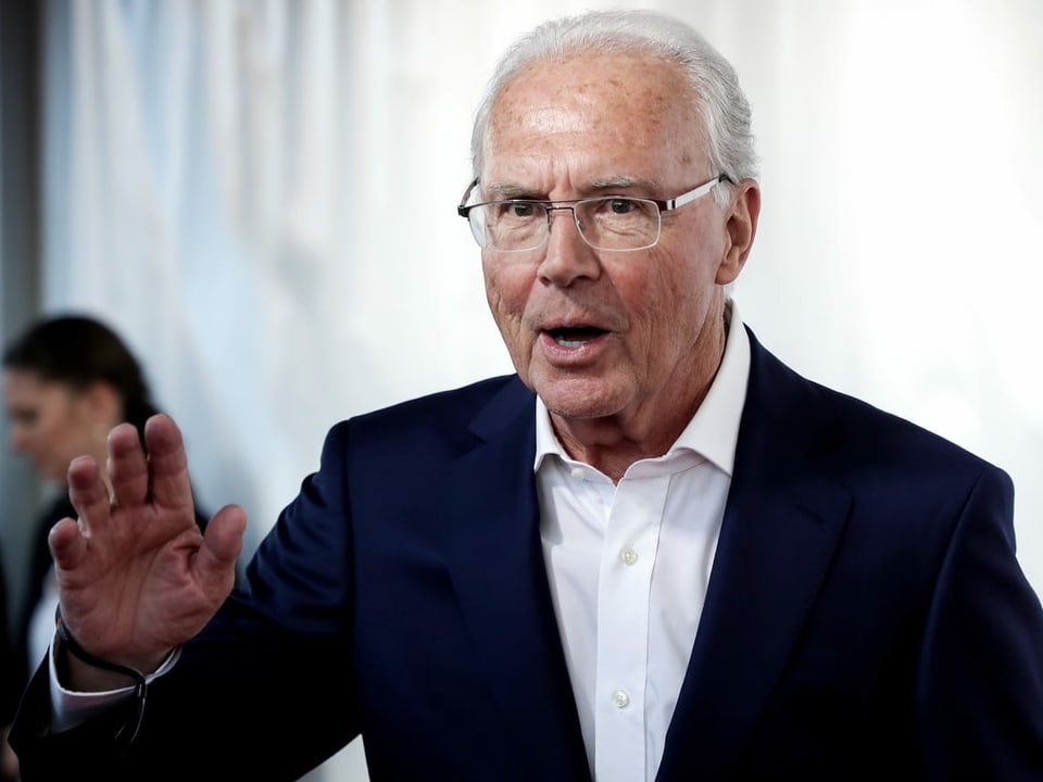 Franz Beckenbauer grüsst an einer Tagung.