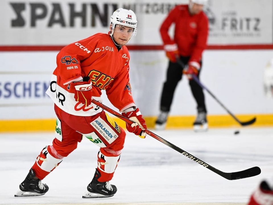 Eishockeyspieler in rotem Trikot auf der Eisfläche.