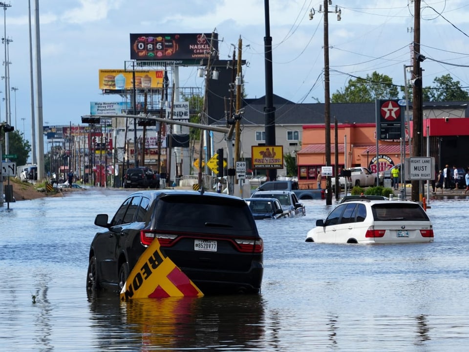 Autos stehen im Wasser auf einer Strasse. 