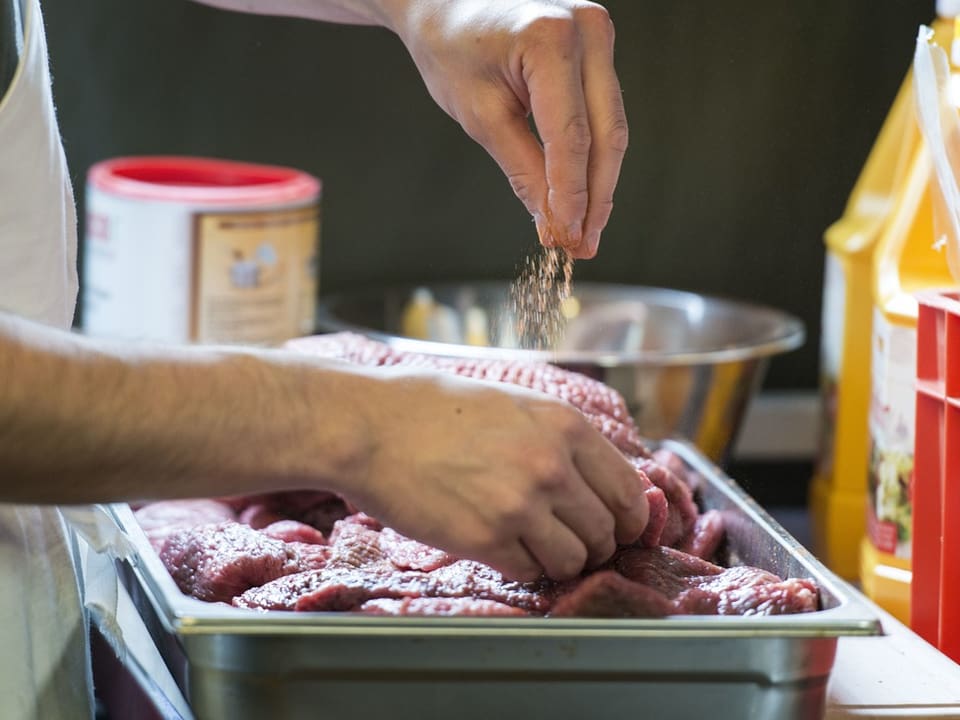 Koch streut Gewürze über Fleisch