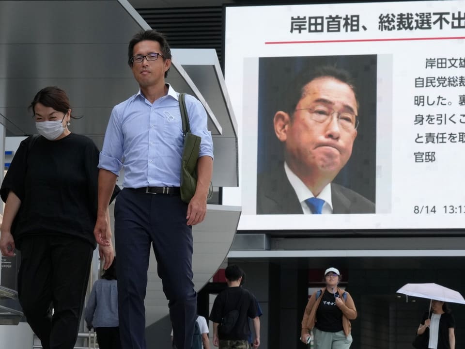 Strassenszene in Tokio, im Hintergrund ein News-Banner mit Kishidas Rücktrittsankündigung.