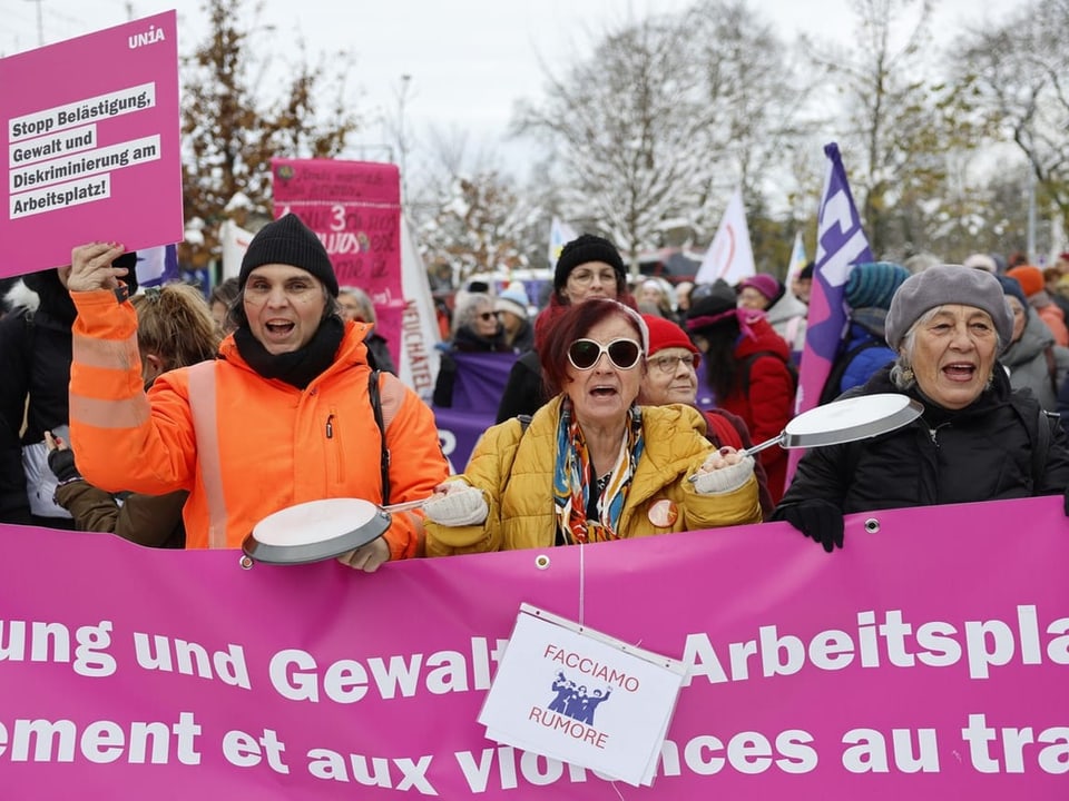 Menschen protestieren mit Schildern und Kochlöffeln.