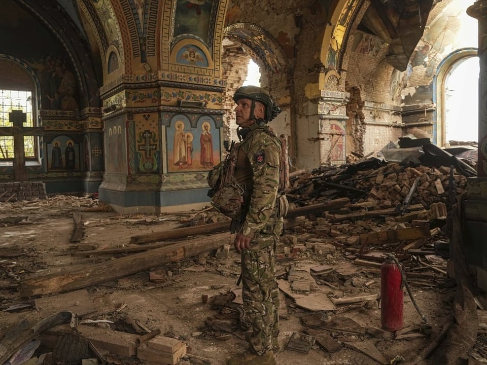 Soldat steht in zerstörter, bemalter Kirche.