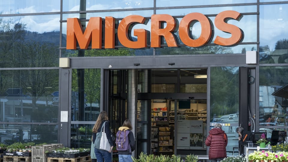 Eingang eines Migros-Supermarkts mit Kunden davor.