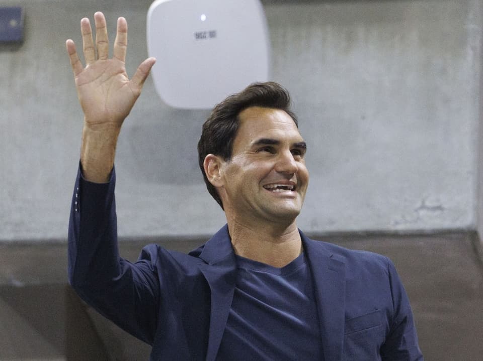 Roger Federer in Anzug, winkt und lächelt.