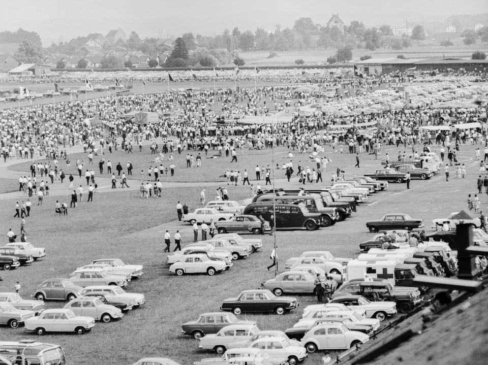 Ein schwarz-weiss Bild des Fluhafens Dübendorf. Zu sehen sind viele parkierte Autos und tausende Zuschauende. 