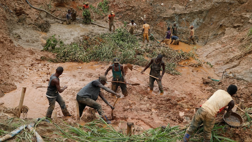 Arbeiter stehen im Wasser mit Schaufeln in einer Mine.