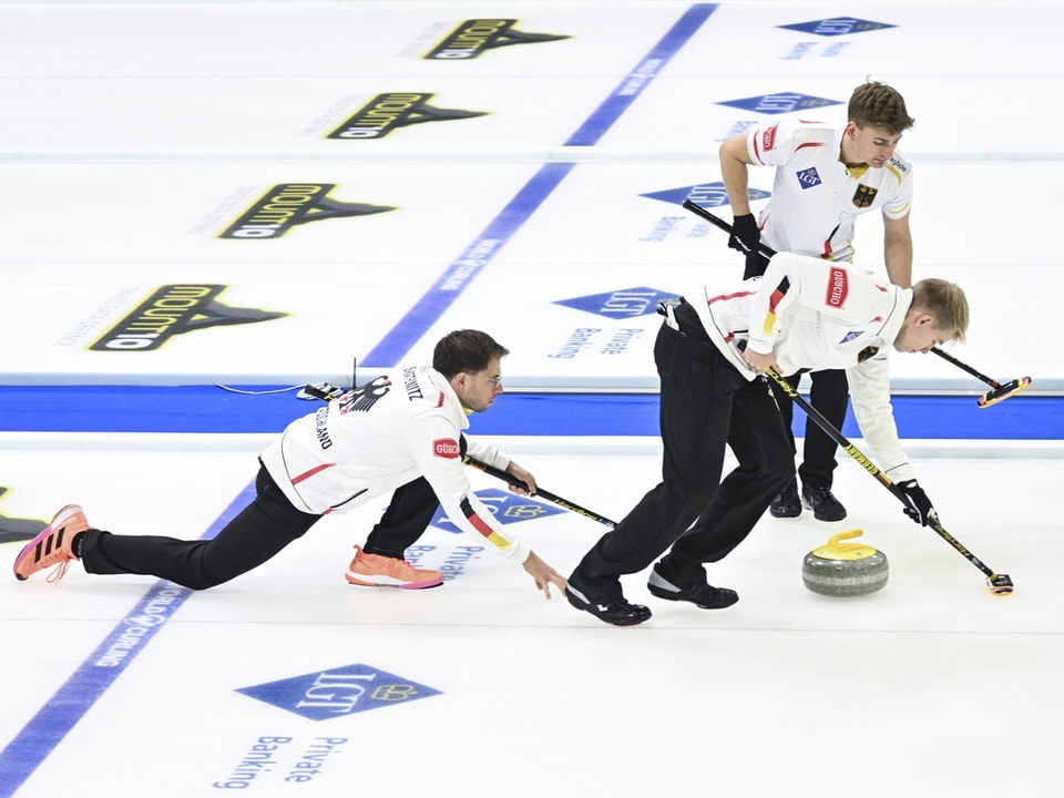 Drei Curling-Spieler in Aktion auf dem Eis.