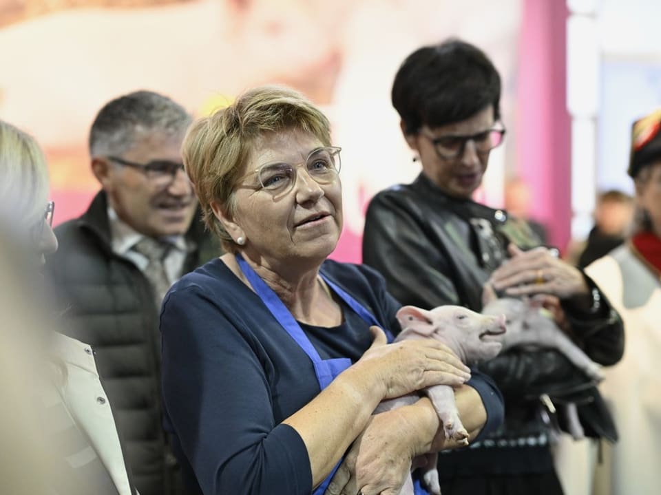 Frau (Bundesrätin Amherd) hält Ferkel auf einer Veranstaltung.