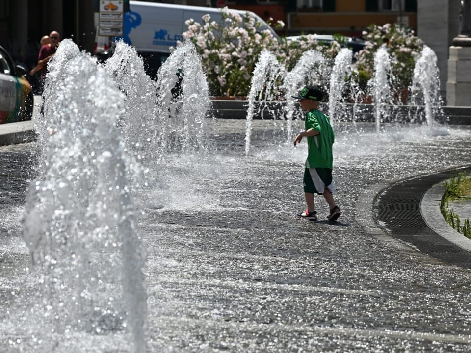 Kind spielt in einem öffentlichen Springbrunnen.