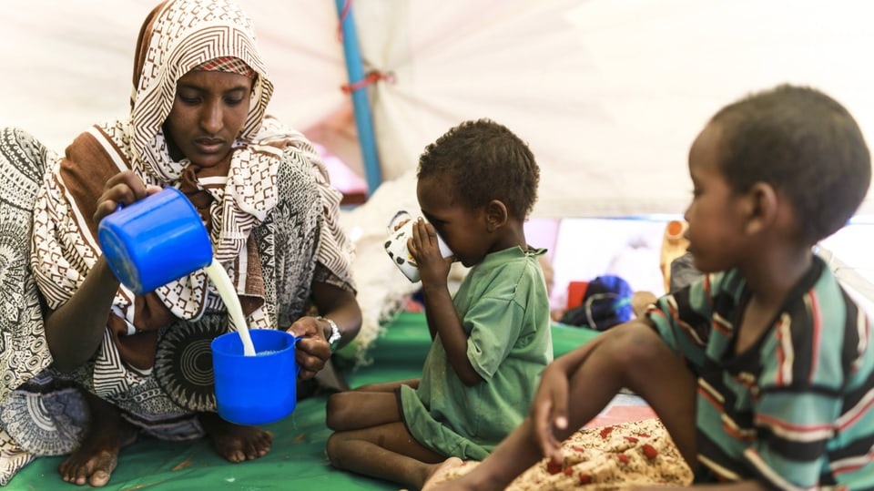 Eine Mutter bereitet ihren Kindern Milch aus Milchpulver zu.