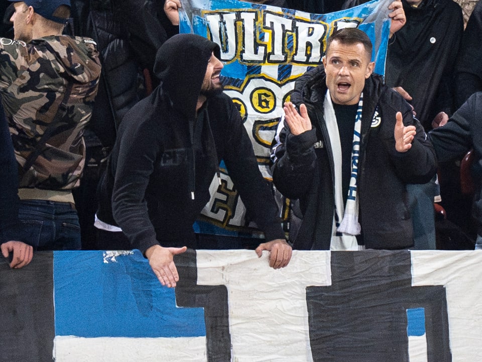 Fussballfans mit Banner im Stadion.