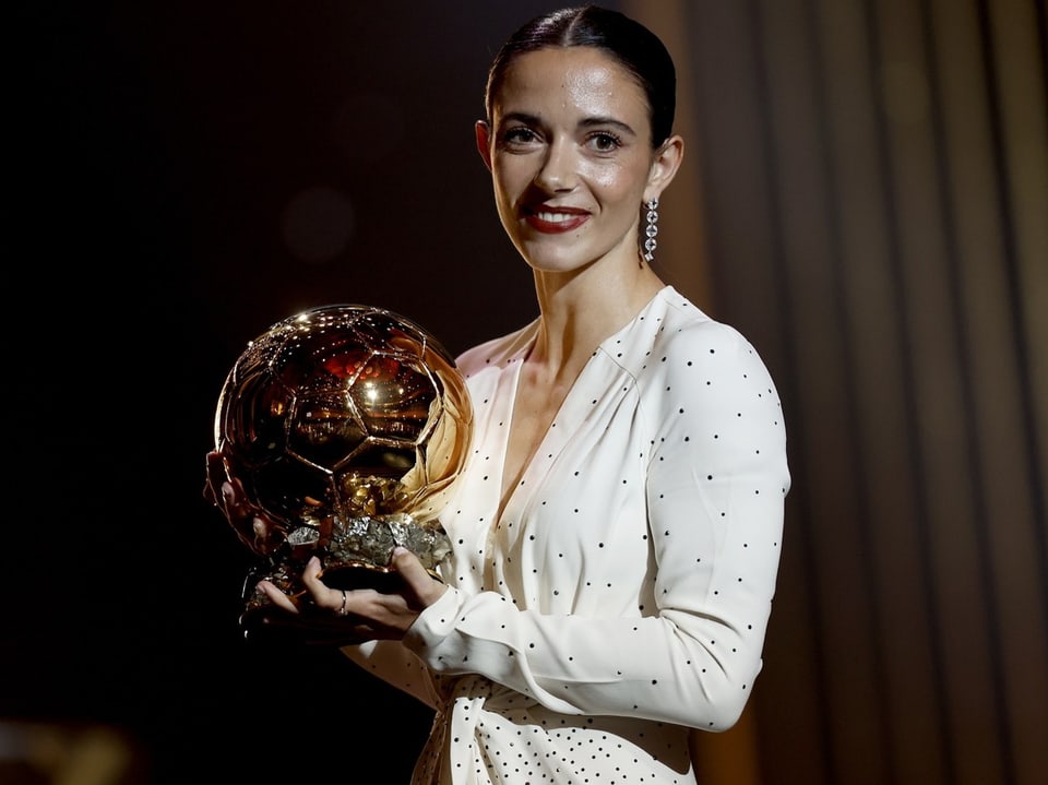 Frau hält goldenen Fussball-Pokal.