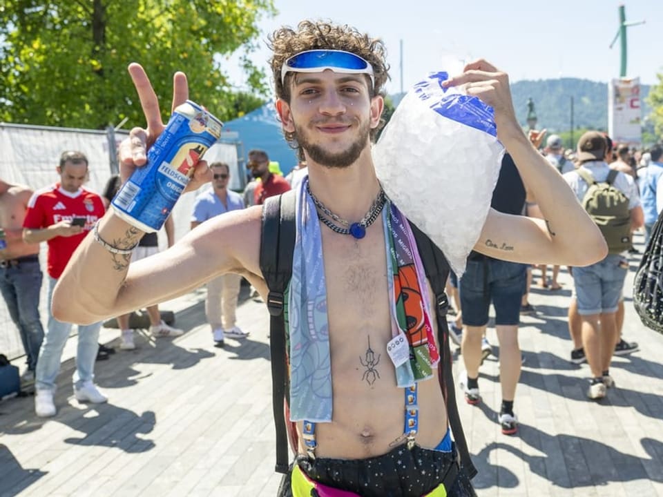 Mann bei einer Outdoor-Party hält eine Dose Biere und eine Tüte Eis hoch.