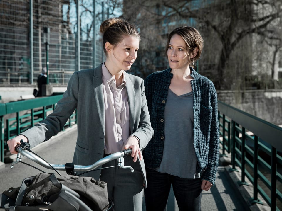 Zwei Frauen auf einer Brücke, die eine stösst ein Fahrrad.