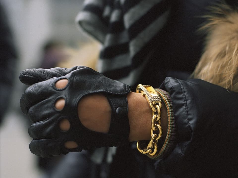 eine Damen trägt Lederhandschuhe und Goldschmuck