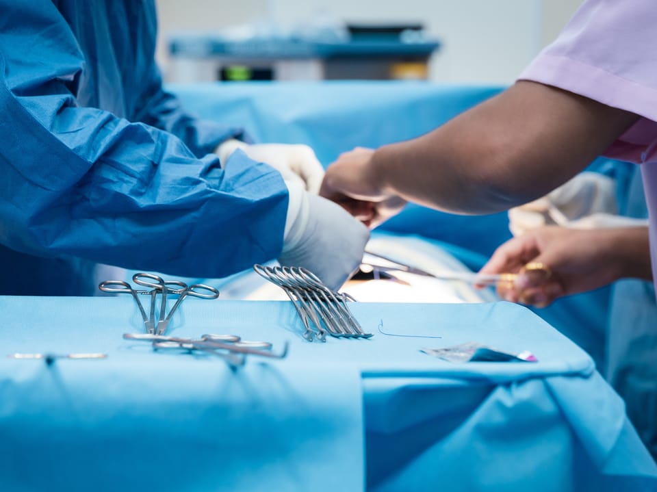 Chirurgen bei der Operation mit chirurgischen Instrumenten auf dem Tisch.