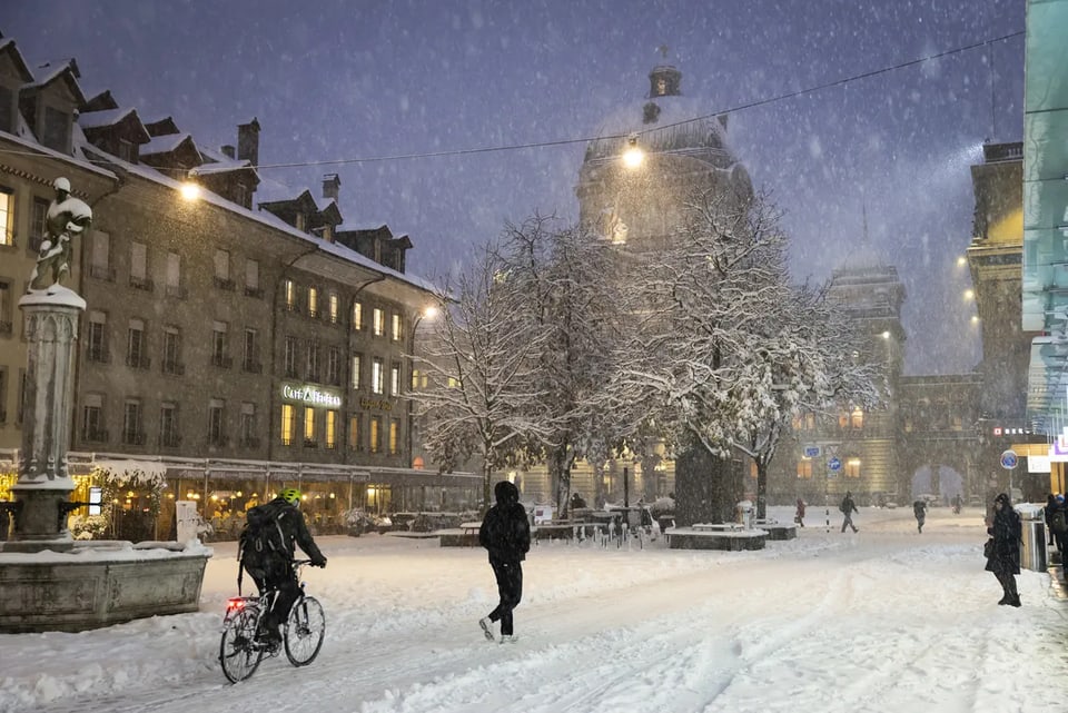 Verschneiter Platz mit Radfahrer und Fussgängern.