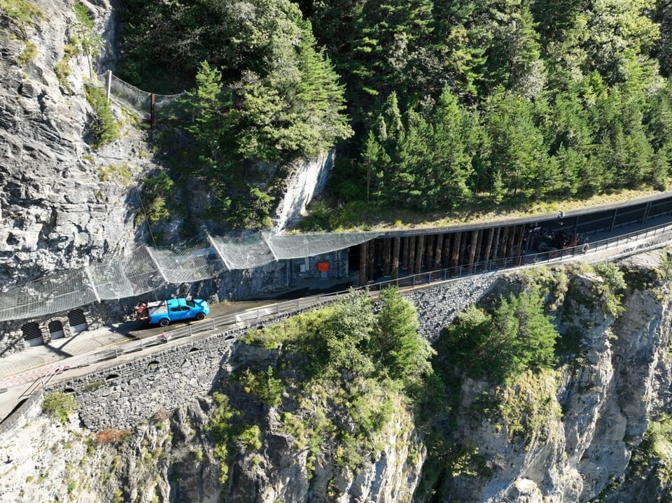 Auto und Motorrad auf schmalem Bergpfad neben steilem Abhang.