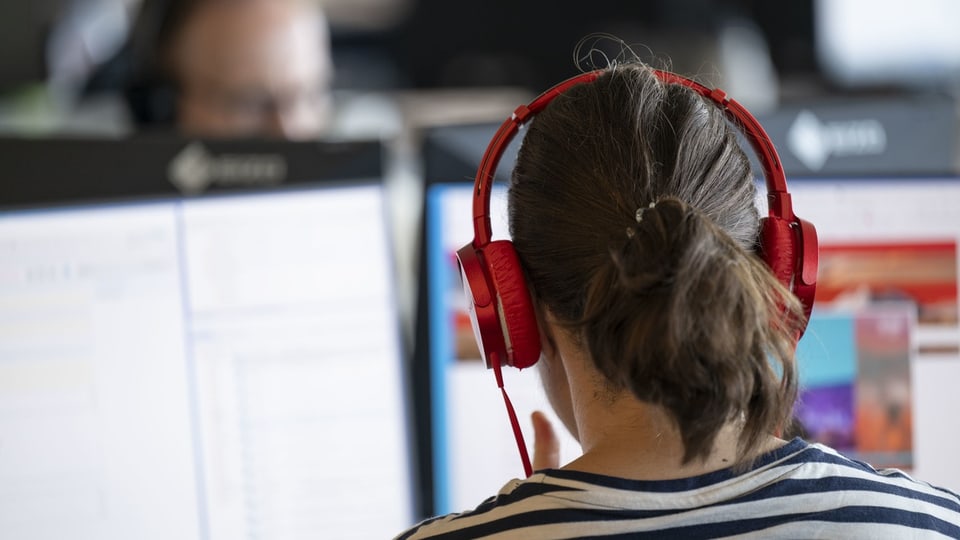 Person mit roten Kopfhörern am Computer.