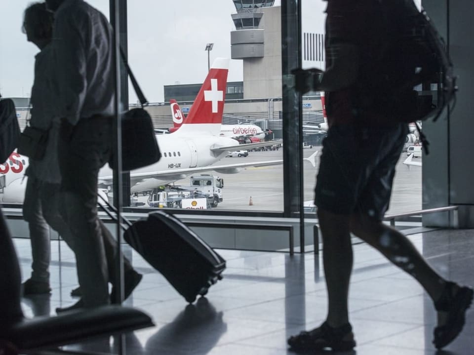 Passagiere mit Gepäck vor einem Swiss-Flugzeug am Flughafen.