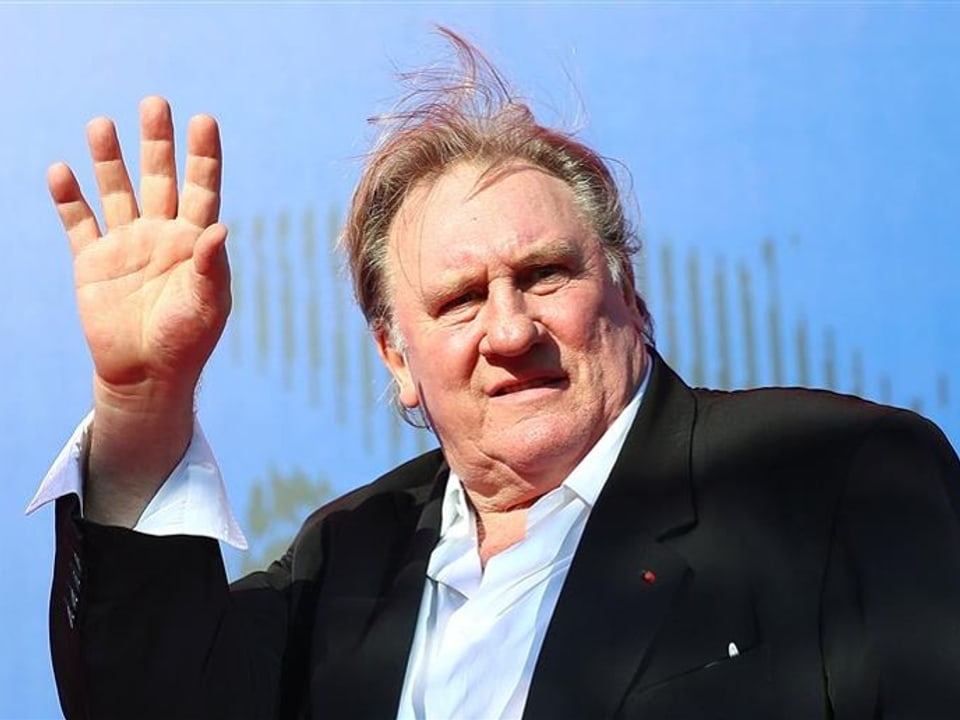 Depardieu winkt in die Kamera.