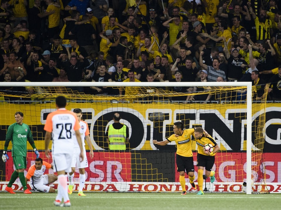 Fussballspieler jubeln vor jubelnden Fans im Stadion.