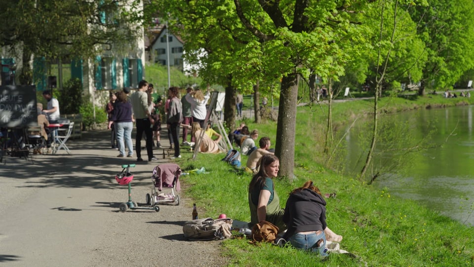 Das Flussufer von Lichtensteig an einem schönen Tag. Menschen sitzen im Gras.