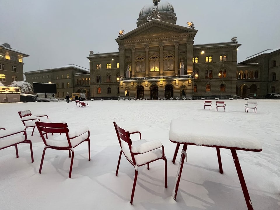 Schneebedeckter Platz mit roten Stühlen vor dem Bundeshaus.